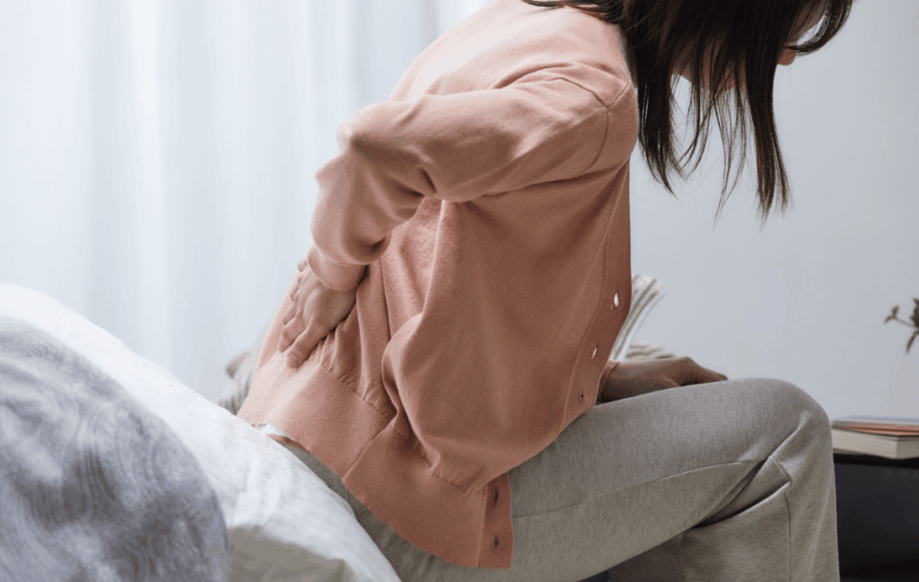 生理前に必ず腰痛になる女性が腰を抑えてうずくまっている姿