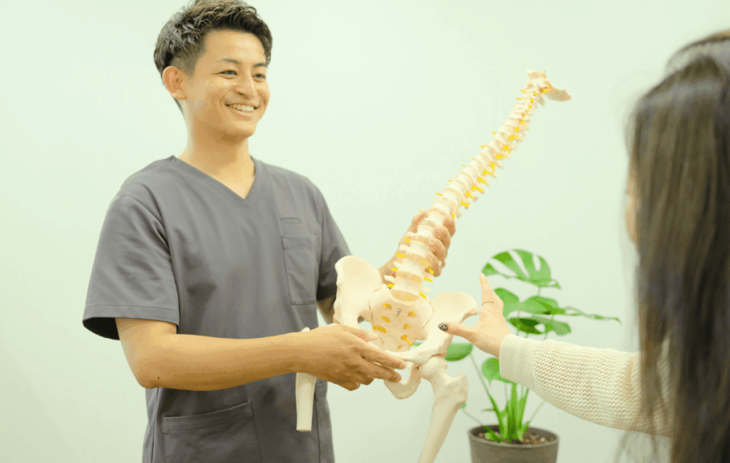 生理前の腰痛の原因と施術方法を女性に説明している施術者の姿