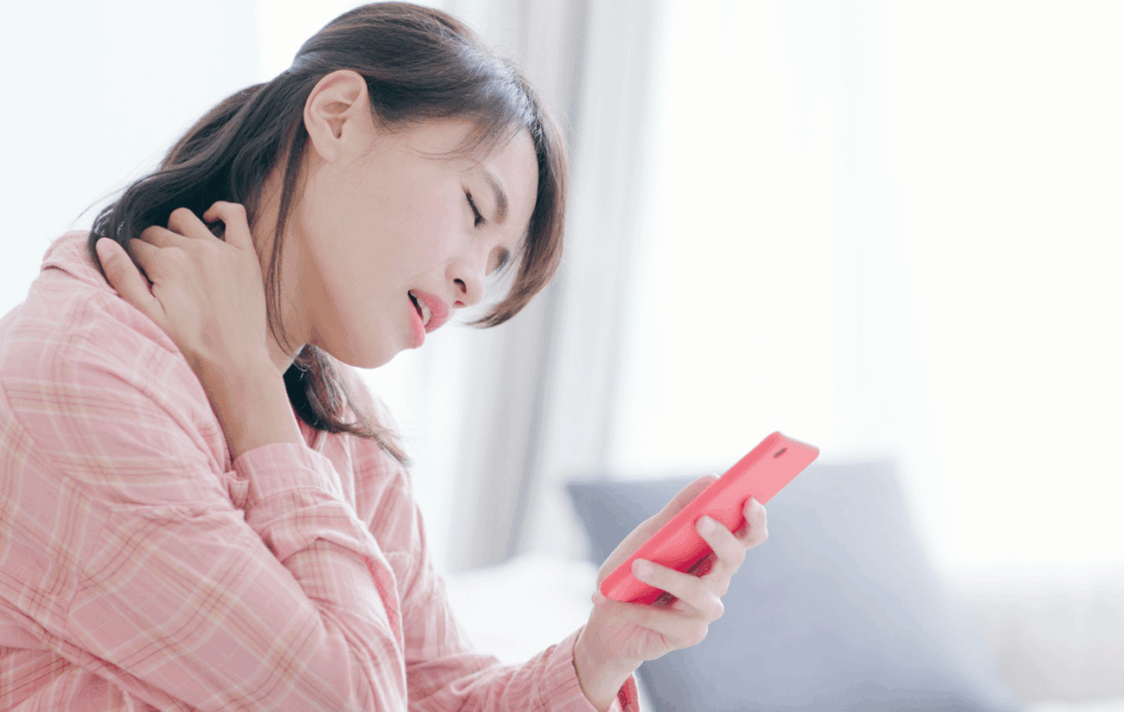 首こりやめまいの原因がストレートネックではないかと考えて携帯で調べている女性の姿