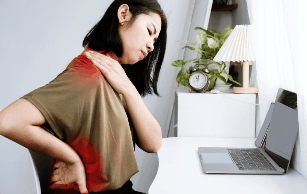 デスクワークをしながら腰痛で悩んでいる５０代の女性の姿