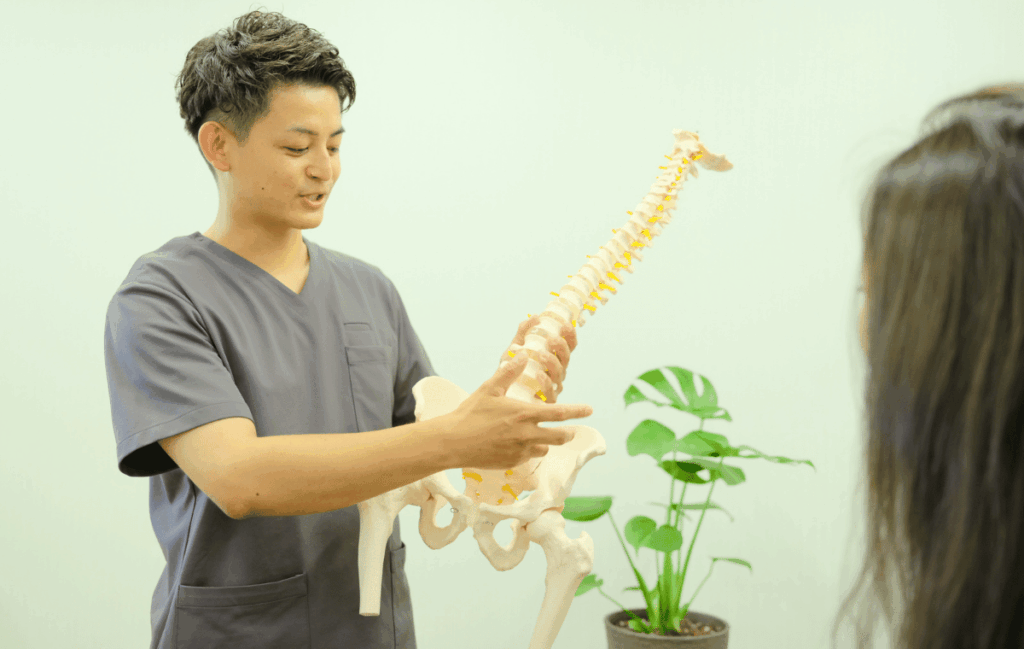 整骨院で患者さんに腰痛の原因を説明している施術者の姿