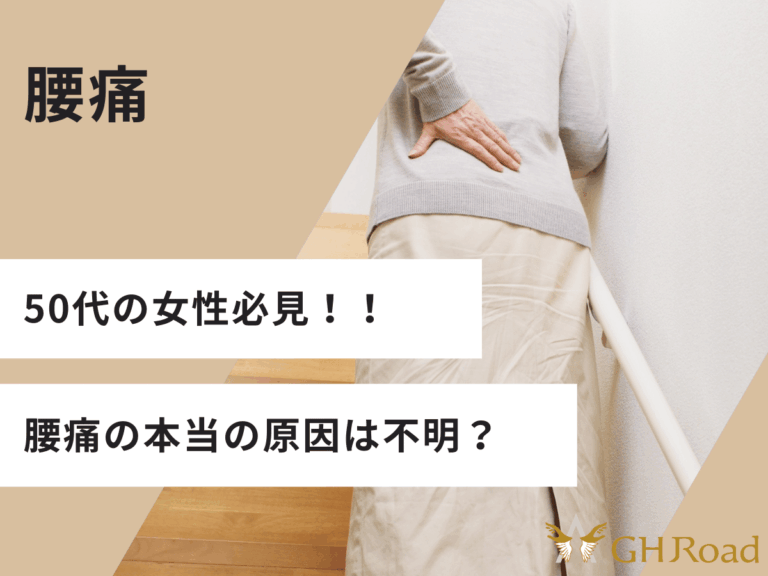 ５０代の女性が階段を上りながら腰に手を当てて腰痛を訴えている姿
